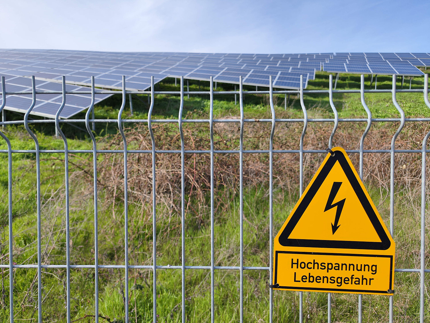 Blick auf einen Zaun mit dem Schild Hochspannung Lebensgefahr