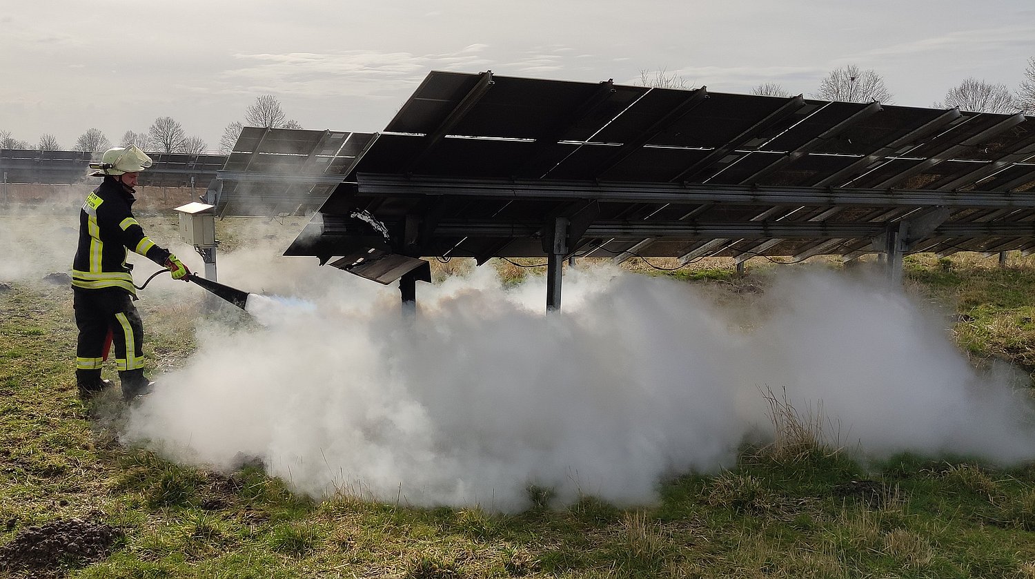 Feuerwehrmann löscht in einem großen Solarpark, viel weißer Rauch